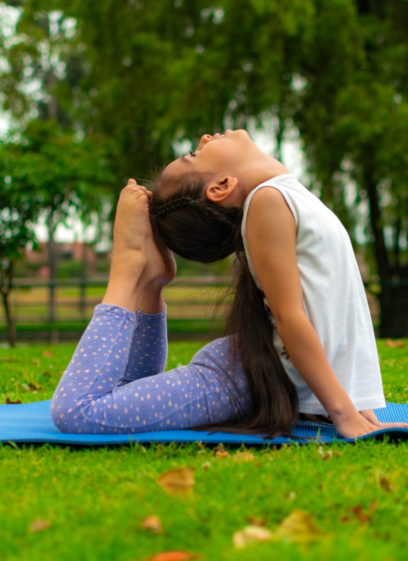 A closeup shot of a cute Latin girl practicing yoga in a park
